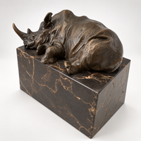 Liegendes Nashorn aus Bronze auf dunklem Marmorsockel in schräger Ansicht