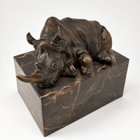 Liegendes Nashorn aus Bronze mit langem Horn auf Marmorsockel in schräger Vorderansicht