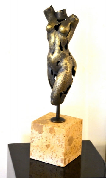 Abstrakter Frauentorso aus Bronze in beleuchteter Gesamtansicht mit Metallhalterung und kubischem Steinsockel auf dunklem Podest.