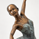 Nahaufnahme von Gesicht und Oberkörper der Bronze-Ballerina mit warmen Bronzetönen und grün patiniertem Ballettkleid.