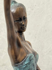 Nahaufnahme des Gesichts und Oberkörpers der Bronze-Ballerina mit erhobenem Arm.