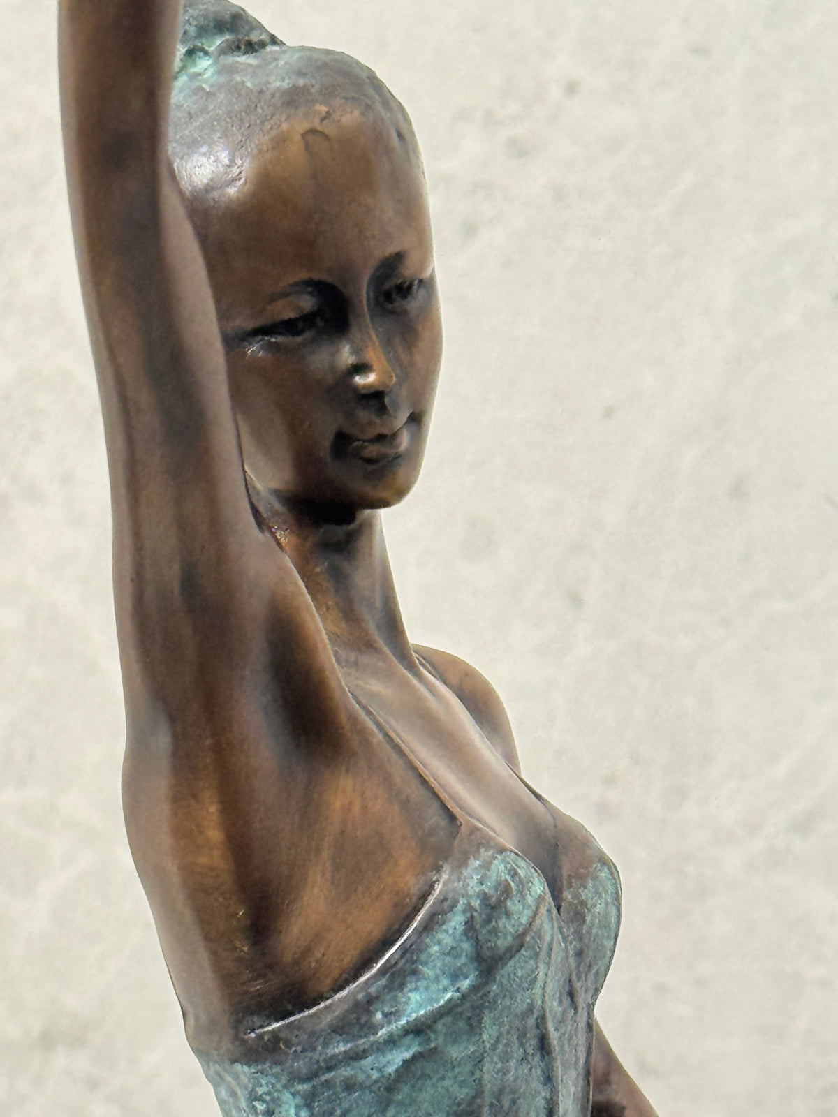 Nahaufnahme des Gesichts und Oberkörpers der Bronze-Ballerina mit erhobenem Arm.
