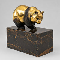 Bronzebär auf dem Marmorsockel aus schräger Vorderansicht.
