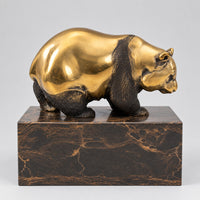 Goldbrauner Bronzebär auf Marmorsockel in seitlicher Ansicht.