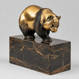 Goldbraun patinierte Bronzefigur eines Bären auf einem dunkel marmorierten Sockel in leichter Vorderansicht.