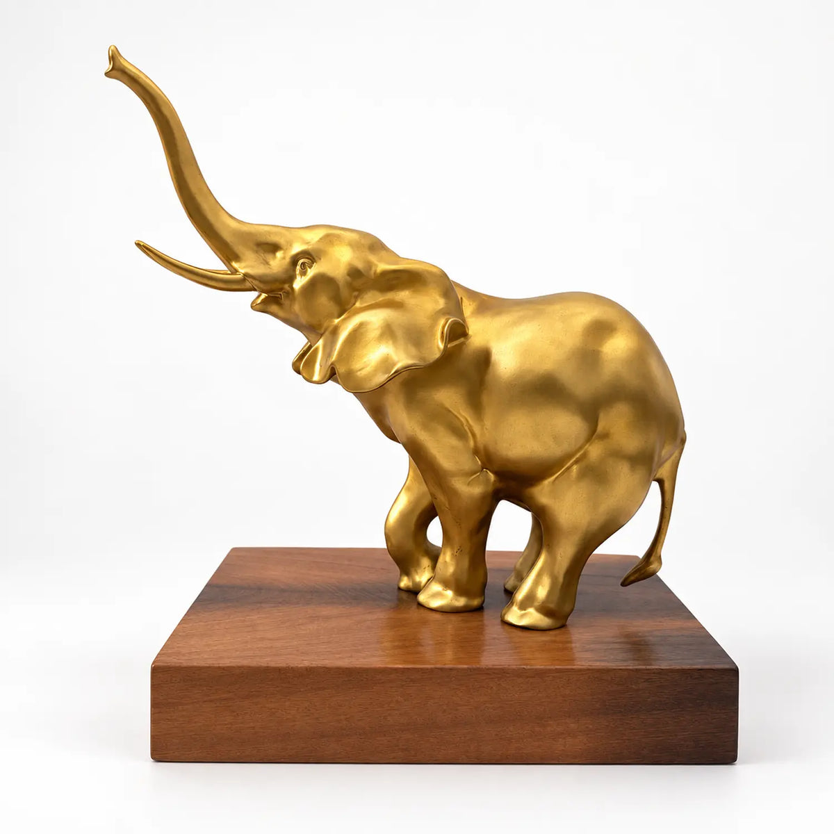Goldfarbene Bronzefigur eines Elefanten mit erhobenem Rüssel und Stoßzähnen auf einem rechteckigen braunen Sockel.