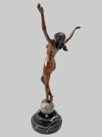 Schräge Rückansicht der Bronzefigur Frau von Raymondo mit erhobenen Armen auf türkisfarben patinierter Kugel.