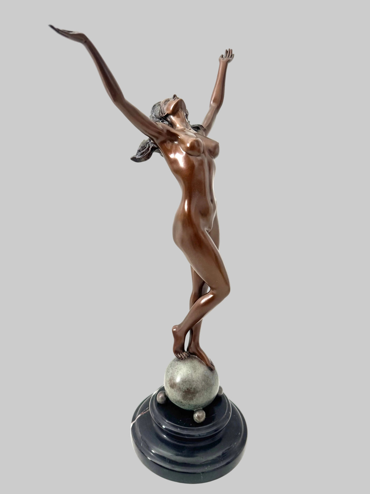 Schräge Gesamtansicht der Bronzefigur Frau mit erhobenen Armen und geschwungener Körperhaltung auf einer Kugel.