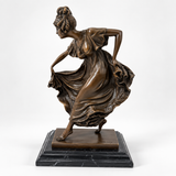 Bronzefigur einer Tänzerin mit schwingendem Kleid auf schwarzem Marmorsockel, schräg von vorn.