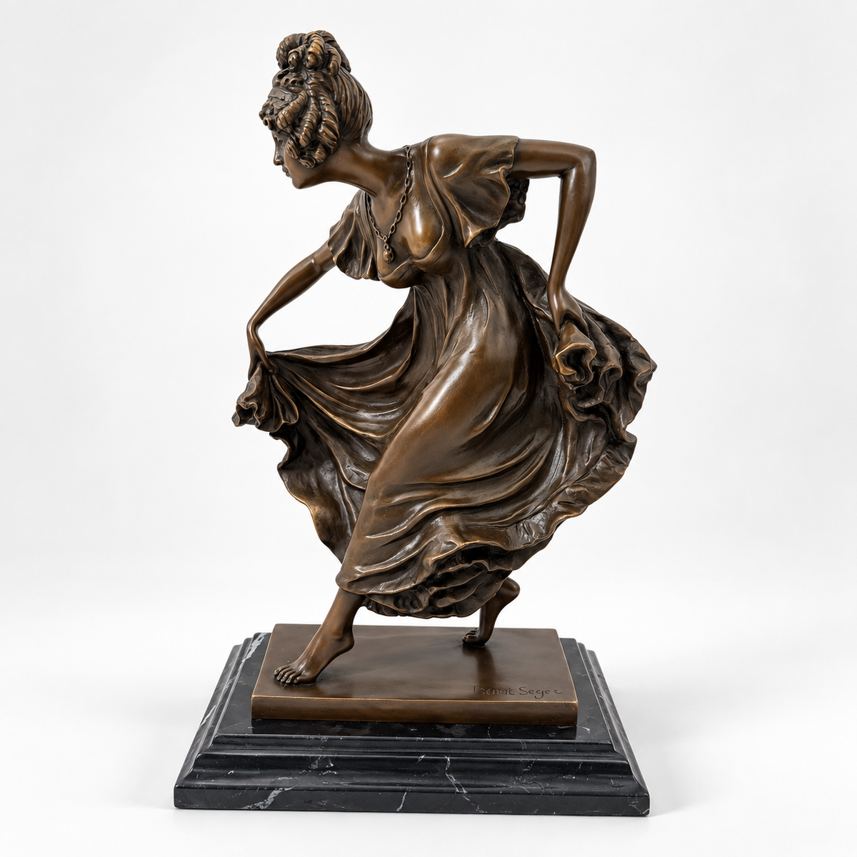 Bronzefigur einer Tänzerin mit schwingendem Kleid auf schwarzem Marmorsockel, schräg von vorn.