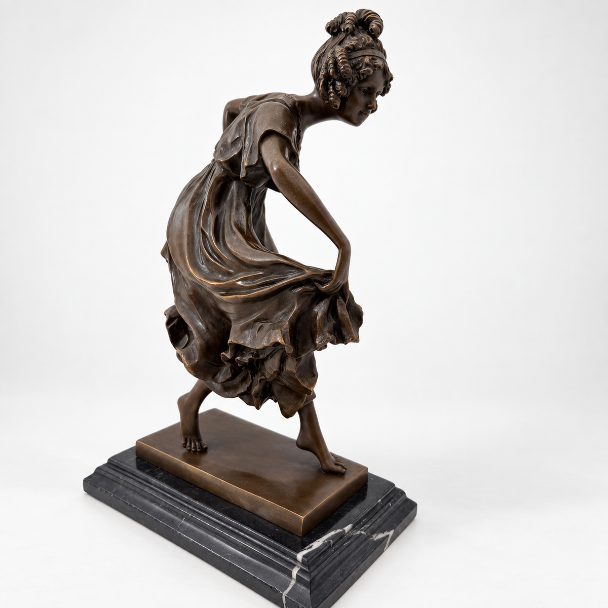 Schräge Seitenansicht der Tänzerin aus Bronze mit nach vorn geneigtem Oberkörper und angehobenem Rock.