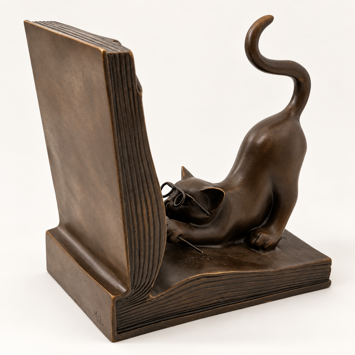 Bronzeskulptur einer Katze mit Brille, teilweise verdeckt durch die aufgerichtete Buchrückseite links im Bild.
