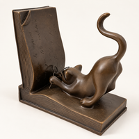Katze aus Bronze mit Brille neben der aufgerichteten Buchseite links, mit Blick auf die gravierte Buchfläche.