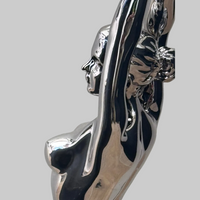Seitliche Detailansicht der Raymondo Skulptur mit Gesicht, hochgestrecktem Arm und reflektierender Chromoberfläche.